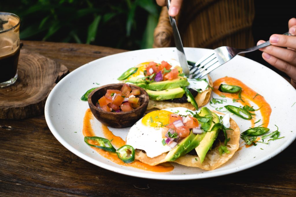 Eating egg, salad, avocado.