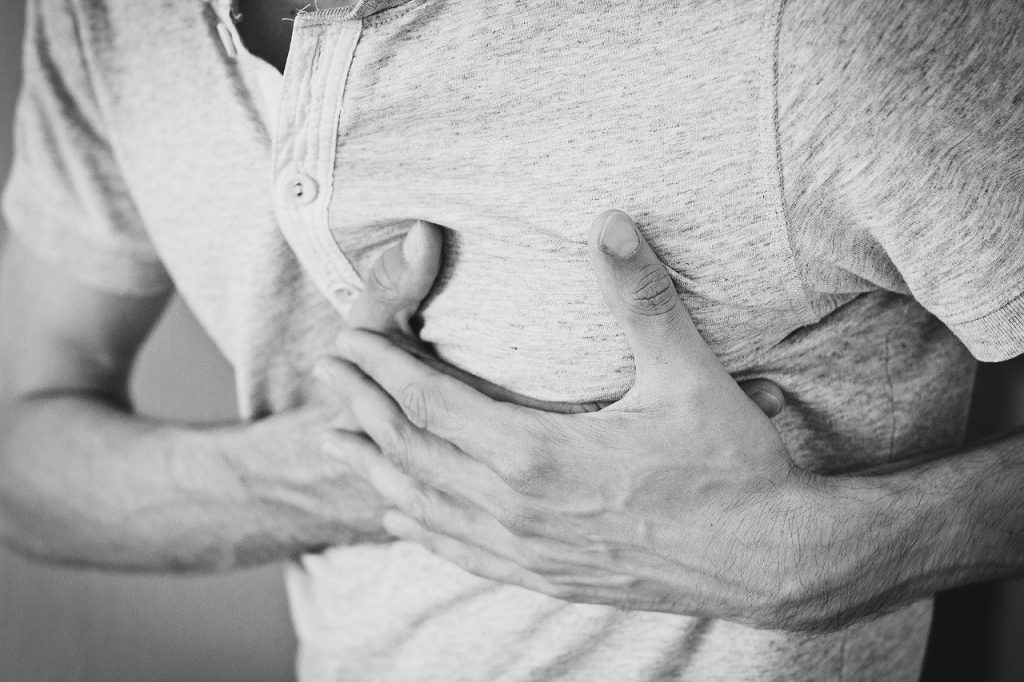 Man clutching his chest, black and white.