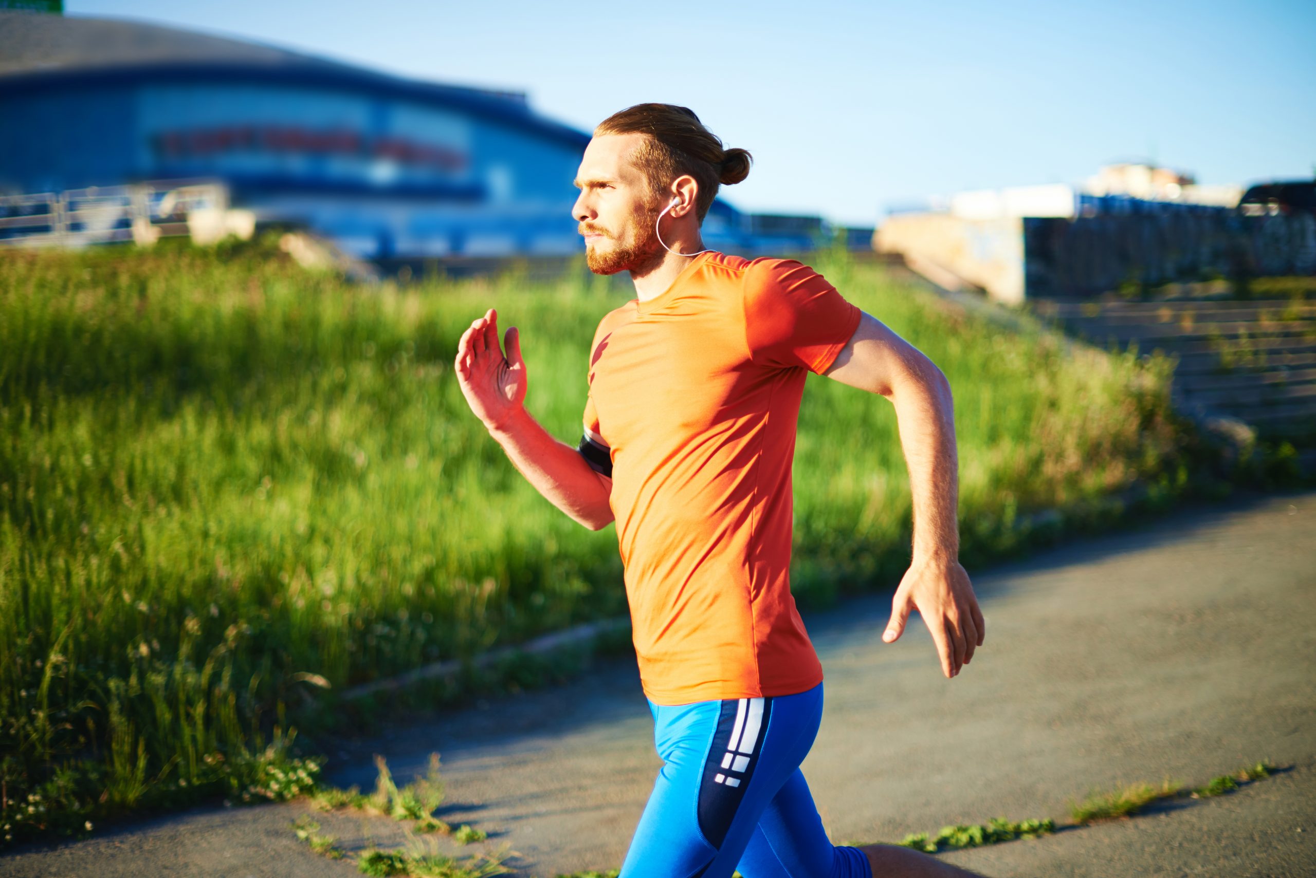 Portrait of young attractive sportsman with earphones running outside
