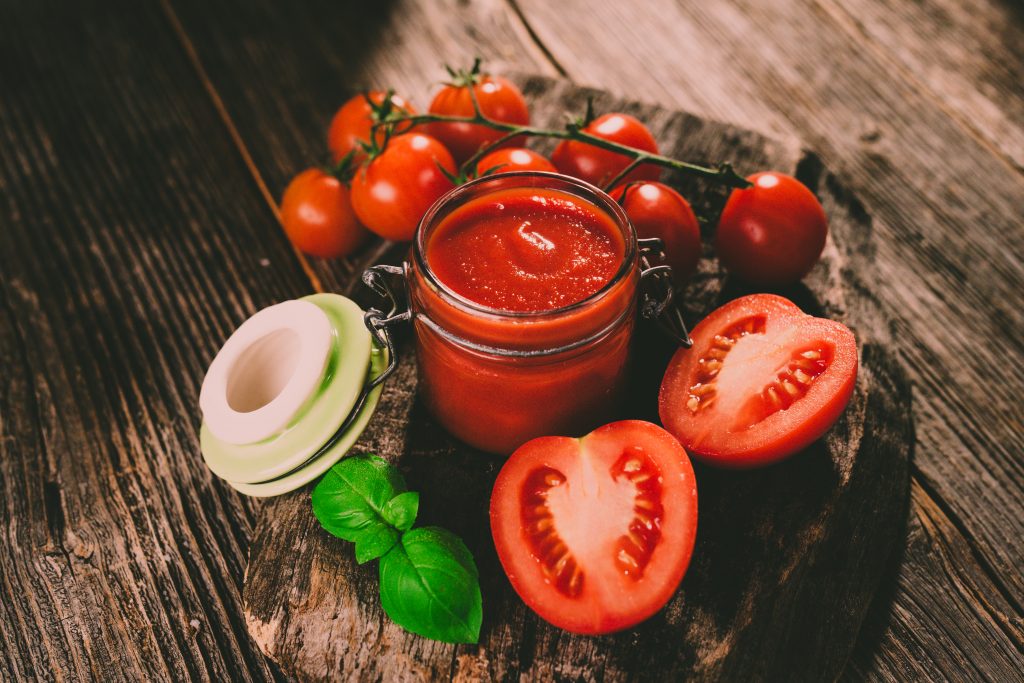 Tomato sauce and fresh tomatos on rustic background