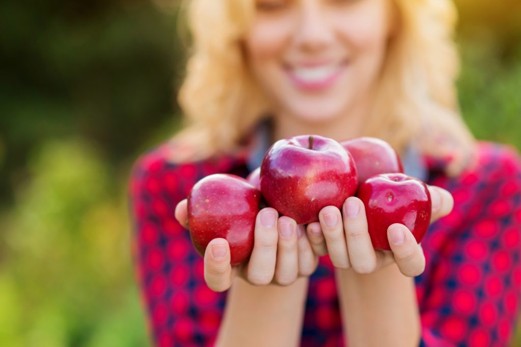 Beautiful woman harvesting apples, eating them
