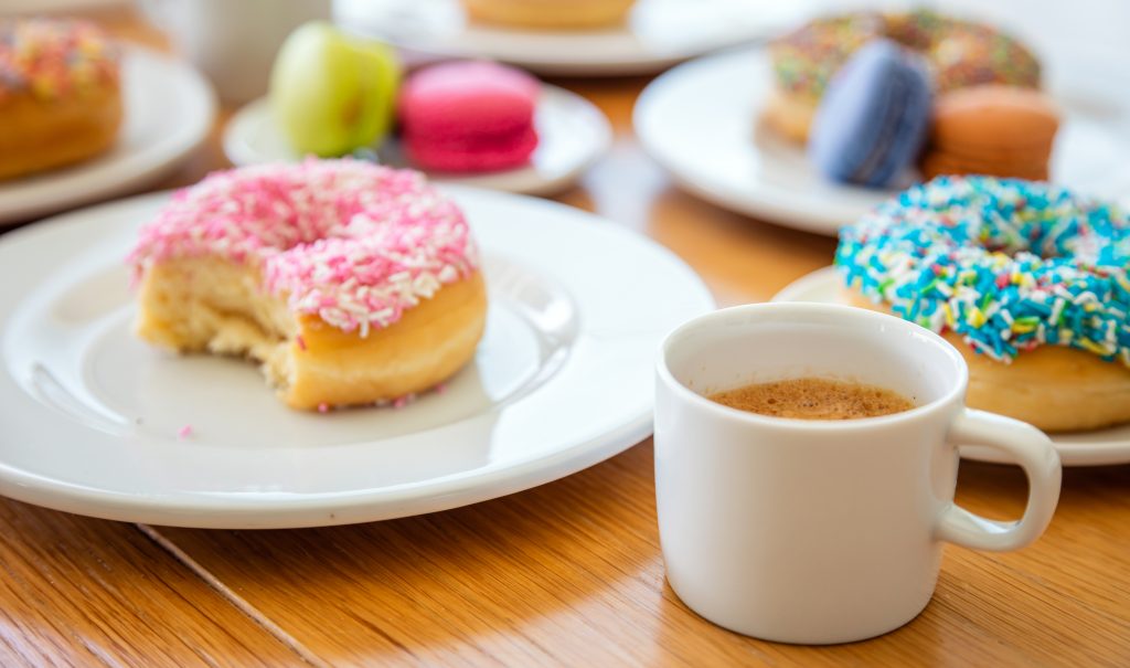 Donuts and french macarons, esresso coffee on wooden table, close up view with details.