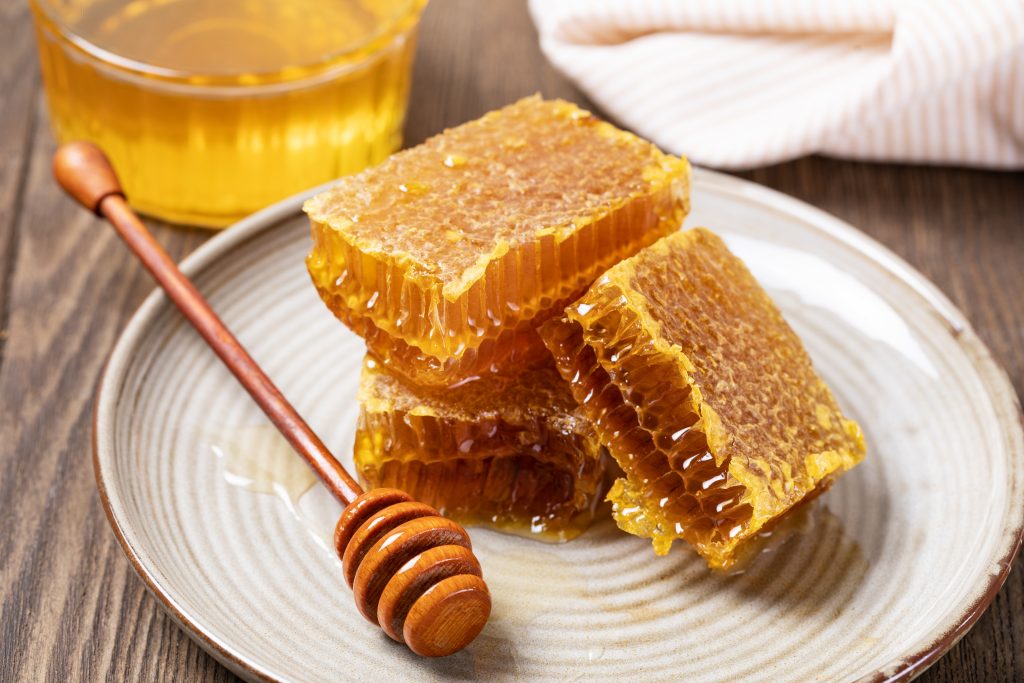 Yellow Honey and Honeycomb slice on a wooden table