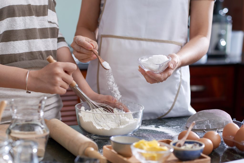 Women adding sugar to recipe.