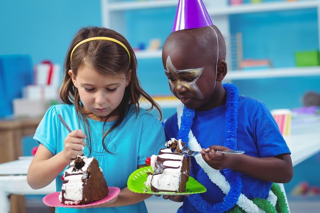 Happy kids eating birthday cake at the party