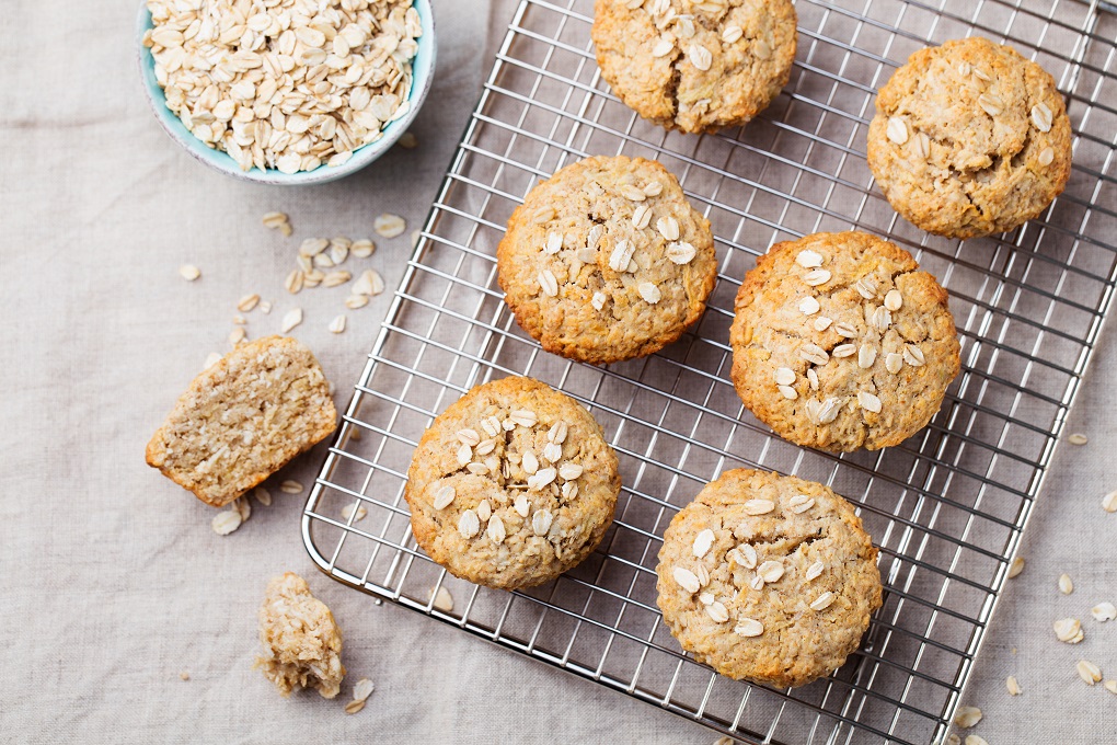 Healthy vegan oat muffins, apple and banana cakes on a cooling rack Grey textile background.