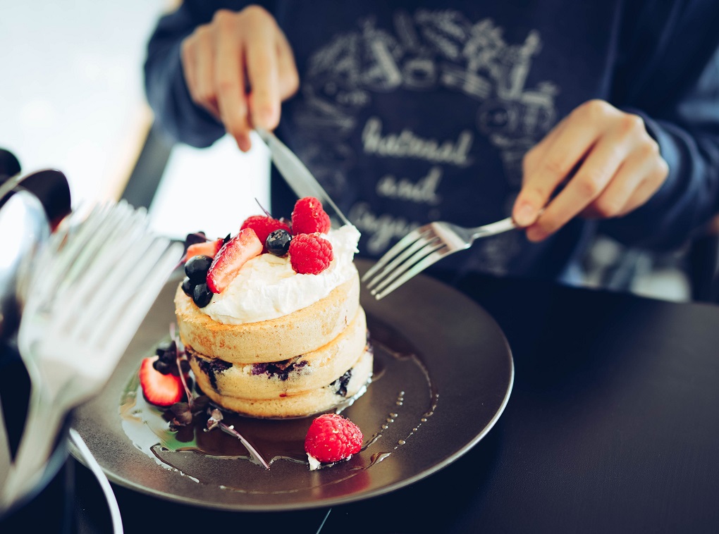 Man cutting into pancakes.