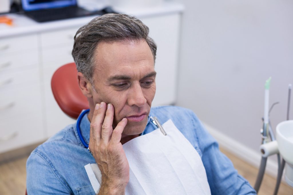 Unhappy man having a toothache in dental clinic