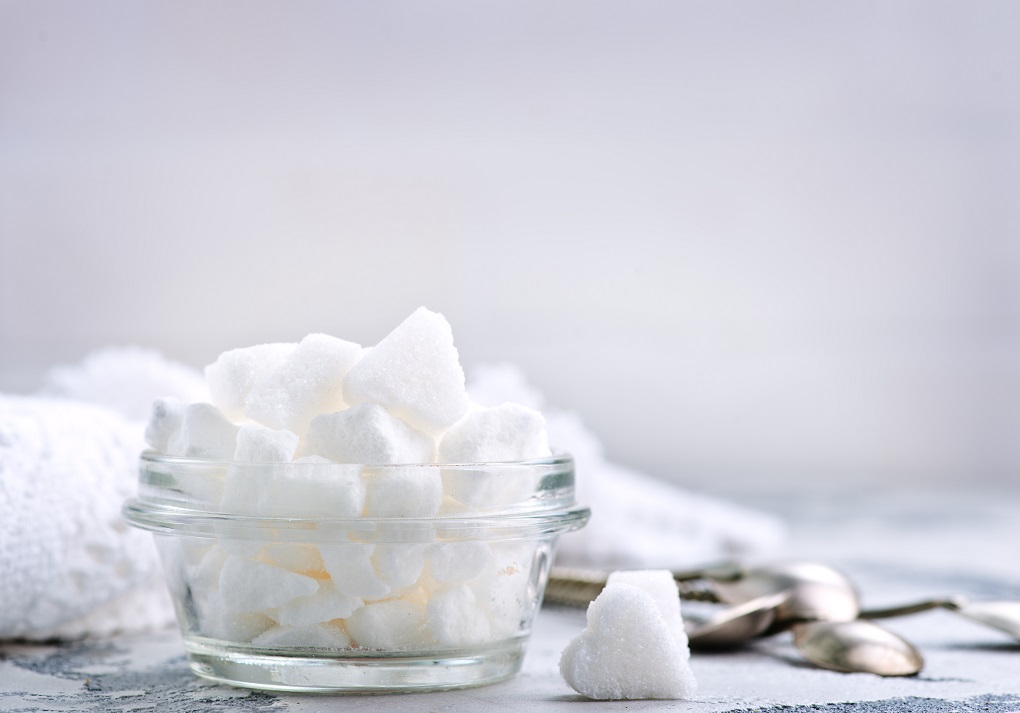 White sugar in glass bowl and on a table