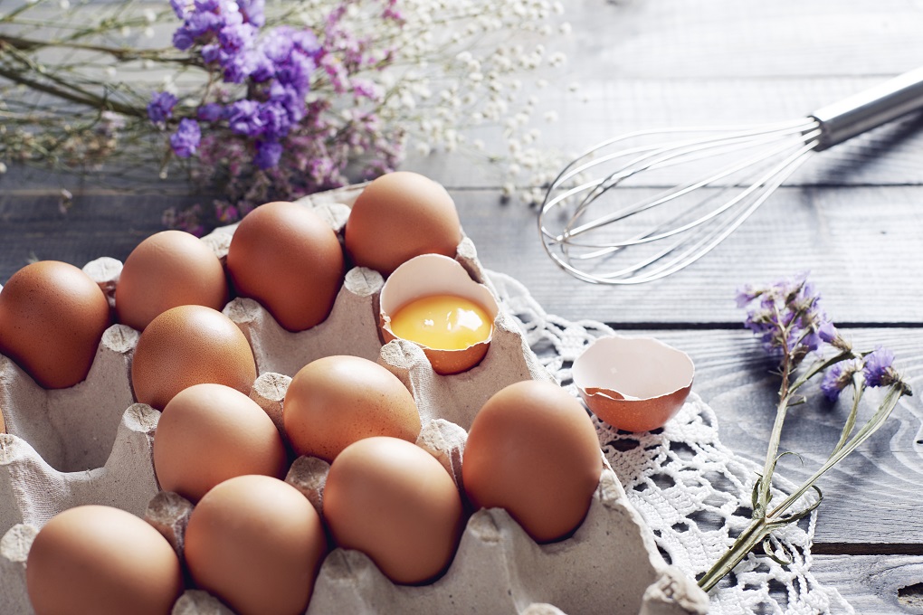 Broken egg among eggs in egg box.