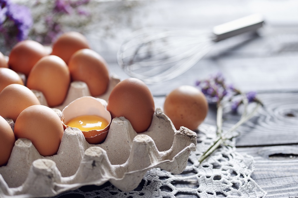 Broken egg among brown eggs in egg box