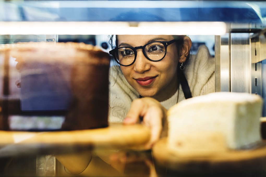 Woman getting cake out of the display fridge