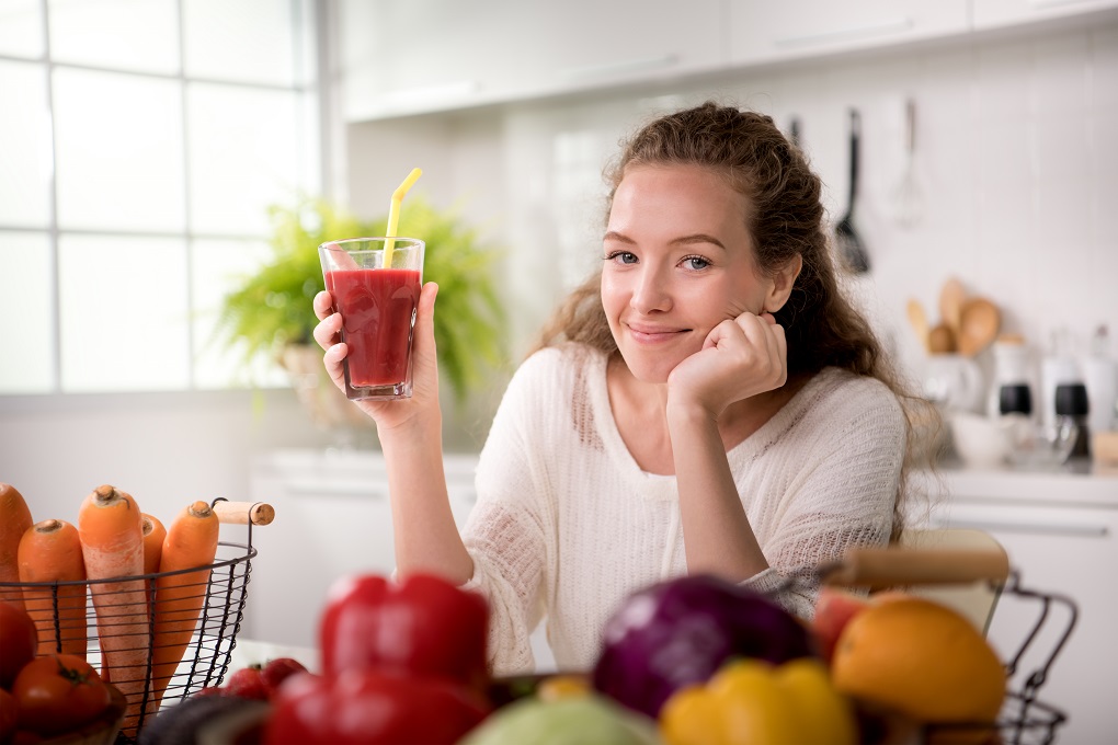 Healthy young woman in a kitchen with fruits and vegetables and juice