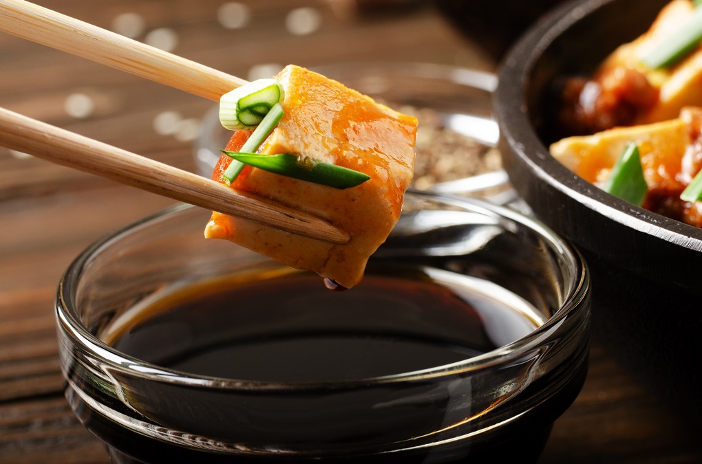 Mapo tofu dish of soybean curd piece being held in chopsticks