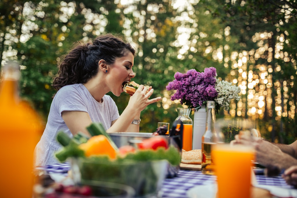 Beautiful young woman eating a burger outdoors