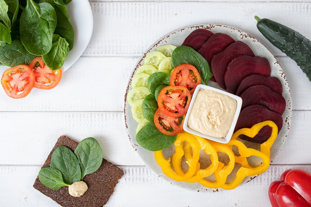 Flat lay of raw vegan food and hummus.