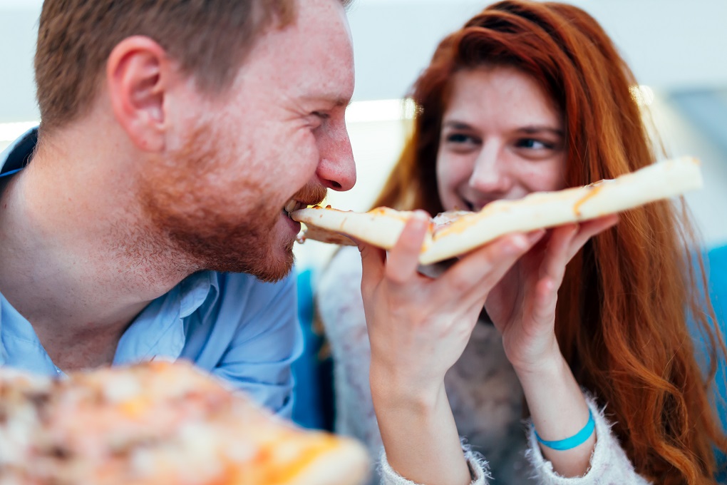 Couple sharing pizza and eating together happily
